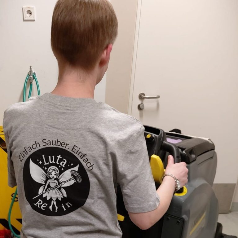 Unterhaltsreinigung, Büroräume, Arztpraxen Person in grauem T-Shirt mit Logo hält eine Reinigungmaschine.